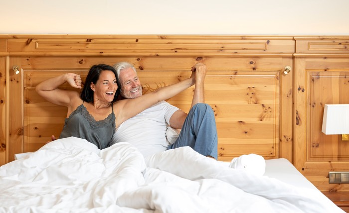 Paar erwacht im gemütlichen Doppelbett beim Urlaub im Hotel Waidmannsheil in Flachau